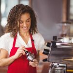 A smiling barista pressing coffee at the coffee shop